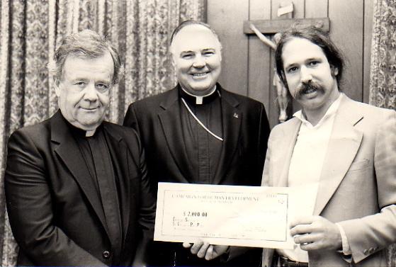 Mark Masselli receiving a check from two priests