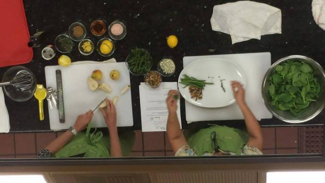 The creation of Virginia and Tara's salad through the demonstration kitchen mirror at G&G Market's Ginger Grille.